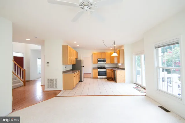a view of a kitchen with kitchen island stainless steel appliances counter space and a window