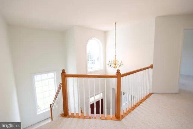a view of a hallway to a bedroom with wooden floor and stairs