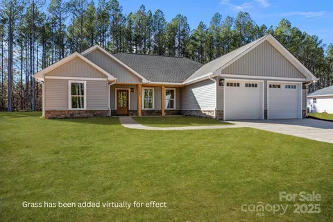 a front view of house with yard and trees in the background