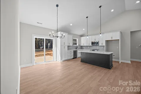 a large kitchen with kitchen island a island a stove a refrigerator a sink a center island and wooden floor