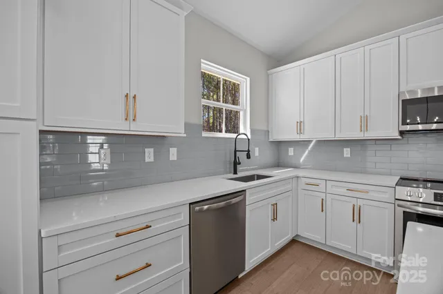 a kitchen with stainless steel appliances granite countertop white cabinets stove a sink and dishwasher