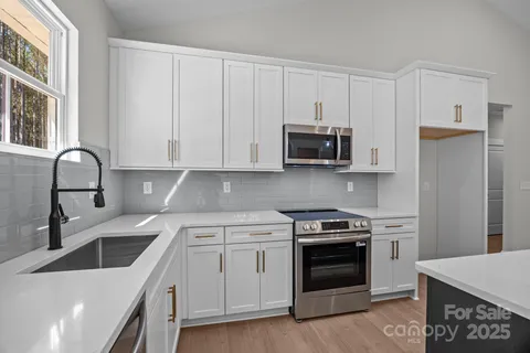 a kitchen with stainless steel appliances granite countertop a stove a sink and a microwave