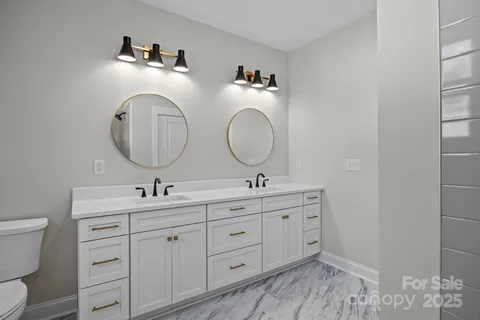 a bathroom with a toilet a double vanity sink and a mirror