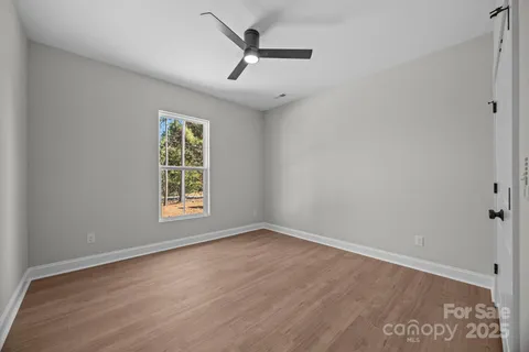 an empty room with wooden floor ceiling fan and windows