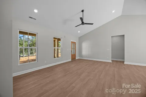a view of an empty room with a window and wooden floor