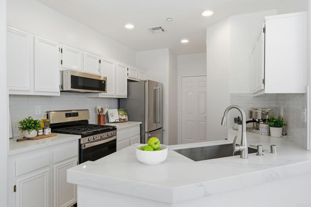 6180 Citracado Circle Carlsbad, CA 92009 - Photo 10 of 42 a kitchen with stainless steel appliances a sink a microwave a refrigerator and cabinets