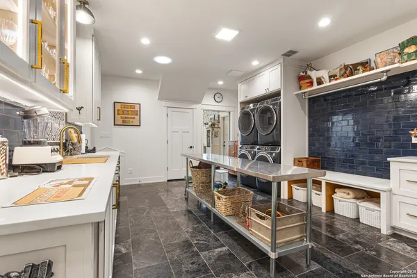 a living room with stainless steel appliances furniture a rug and a kitchen view