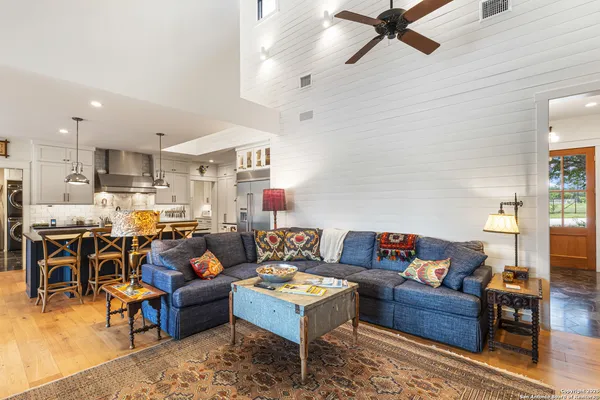 a living room with furniture kitchen view and a wooden floor