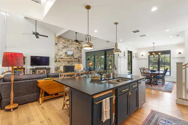 a dining hall with couches a flat tv screen and a dining table with the kitchen view