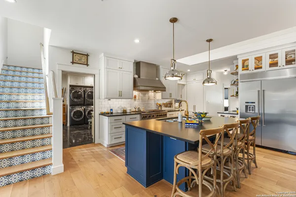 a kitchen with stainless steel appliances kitchen island granite countertop a table chairs and a refrigerator