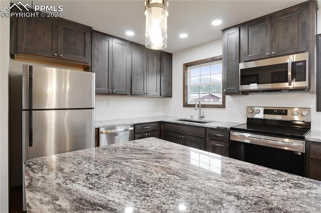 13771 South Hedi Road Sedalia, CO 80135 - Photo 18 of 49 a kitchen with stainless steel appliances granite countertop a refrigerator a stove a sink dishwasher and wooden cabinets with wooden floor