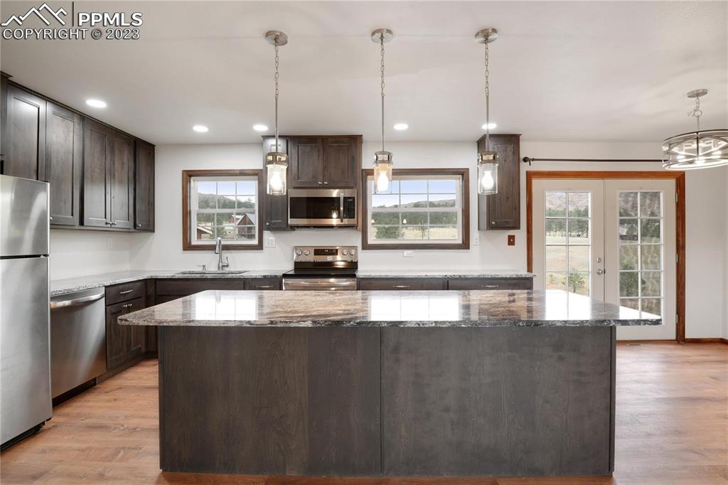 13771 South Hedi Road Sedalia, CO 80135 - Photo 19 of 49 a large kitchen with stainless steel appliances granite countertop a sink a stove and a wooden floors