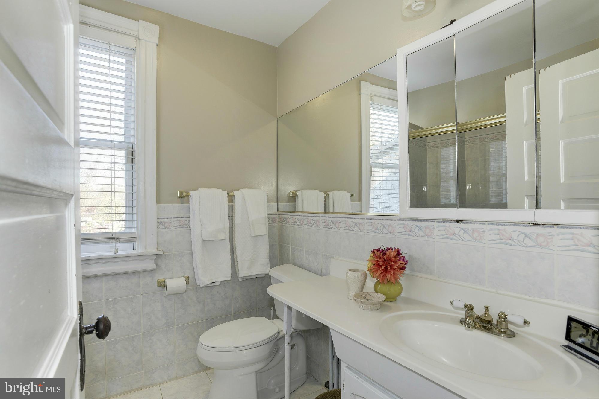 1419 Foxhall Road Northwest Washington, DC 20007 - Photo 11 of 19 a bathroom with a granite countertop sink a toilet and a mirror