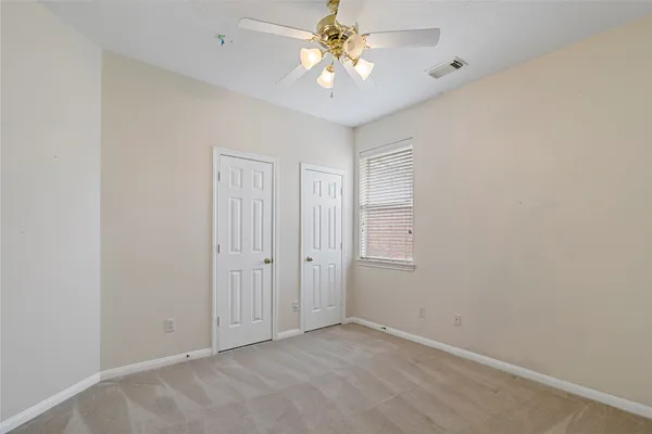 an empty room with closet and a chandelier fan