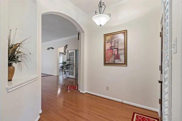 a view of a hallway with wooden floor and a chandelier