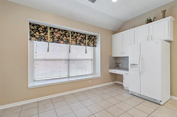 a view of a kitchen with white cabinets and a refrigerator