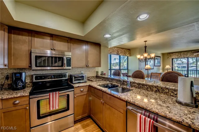 a kitchen with stainless steel appliances granite countertop a stove a sink and a microwave