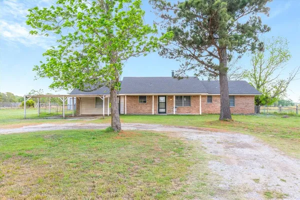 a view of a brick house with a big yard and large trees