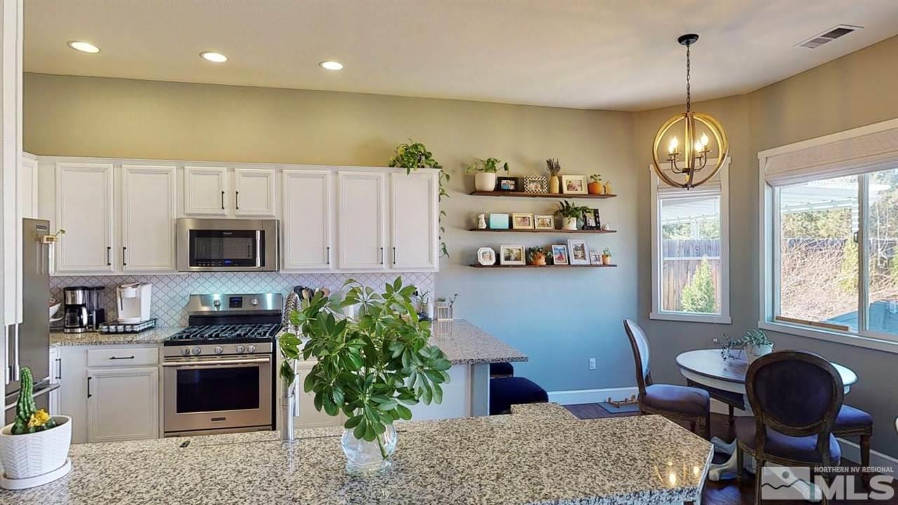 10621 Copper Moon Court Reno, NV 89521 - Photo 11 of 33 a kitchen with stainless steel appliances granite countertop a stove a refrigerator a sink dishwasher a dining table and chairs with wooden floor