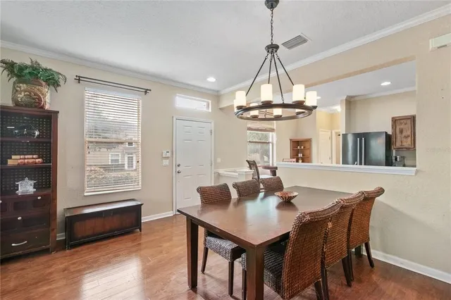 a dining room with wooden floor a chandelier a wooden table and chairs