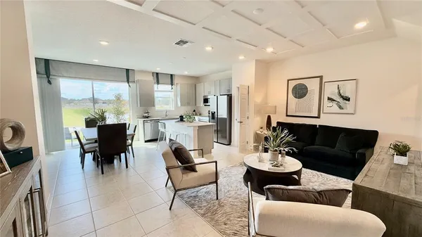 a living room with furniture kitchen view and a large window