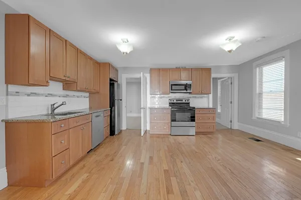 a kitchen with granite countertop a stove top oven a sink dishwasher and a refrigerator with wooden floor