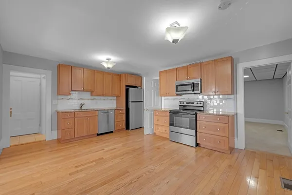a kitchen with stainless steel appliances granite countertop a stove top oven a sink dishwasher and a refrigerator with wooden floor