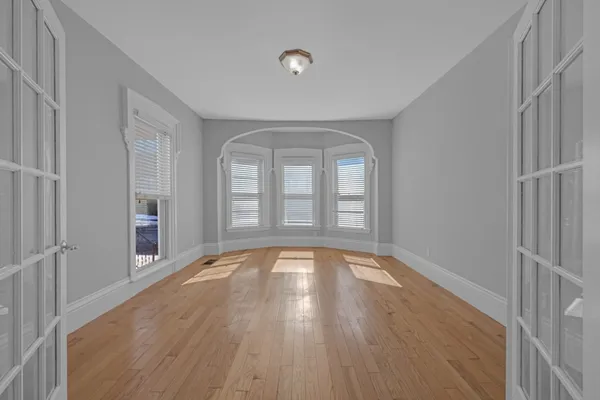 a view of empty room with wooden floor and fan