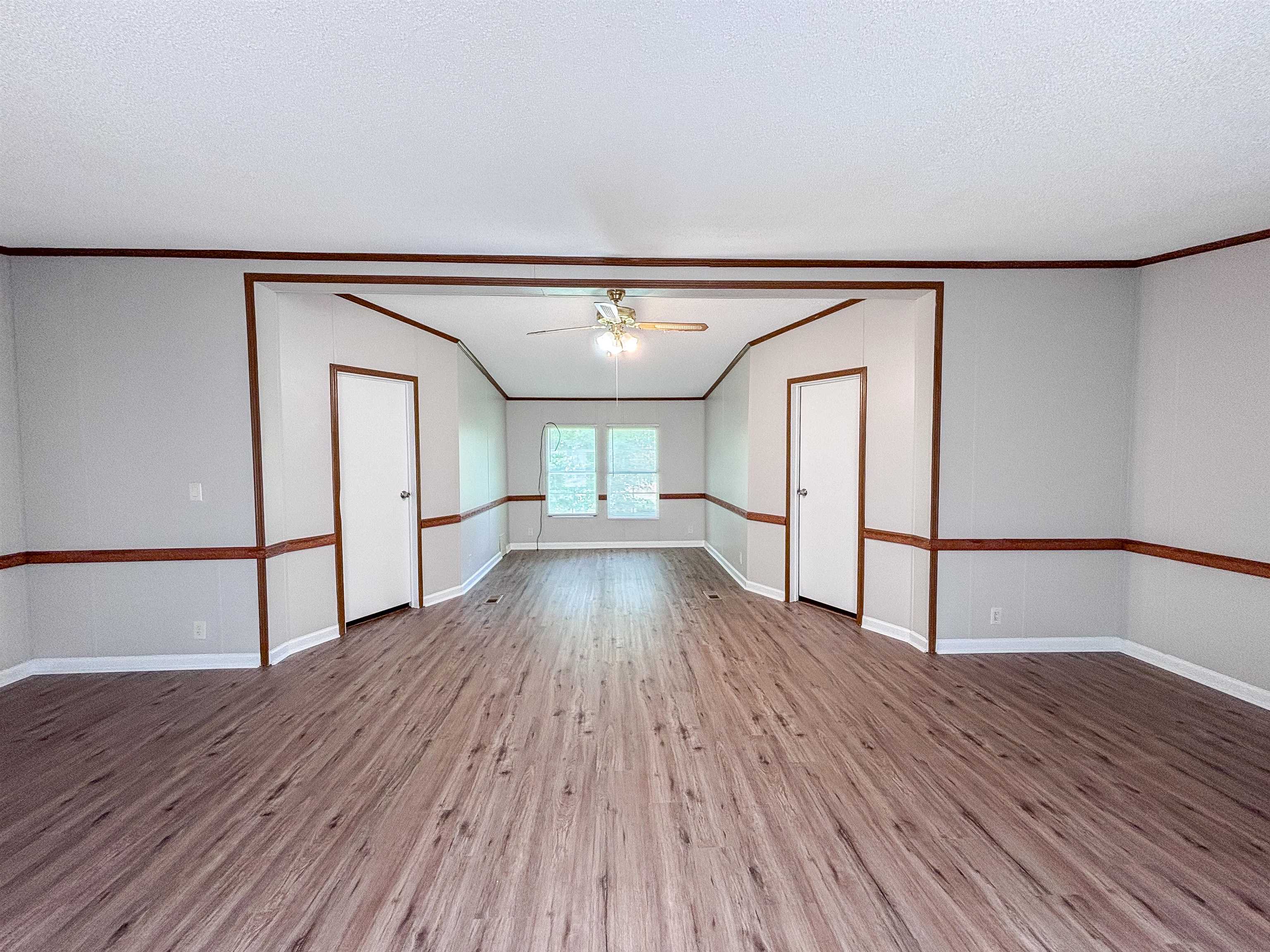 2847 Holly Grove Road Covington, TN 38019 - Photo 16 of 36 Spacious interior featuring wood-finish flooring, light gray walls with wainscoting, and an exposed beam ceiling