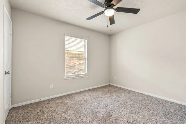 an empty room with a window and a fan