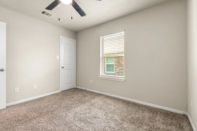 an empty room with a window and ceiling fan