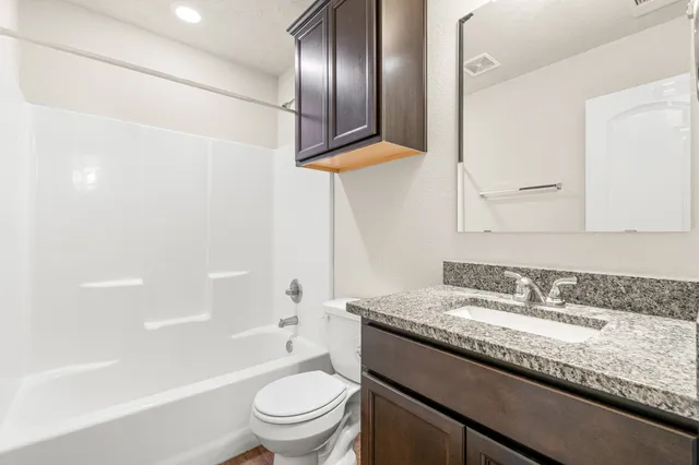 a bathroom with a granite countertop sink toilet and shower