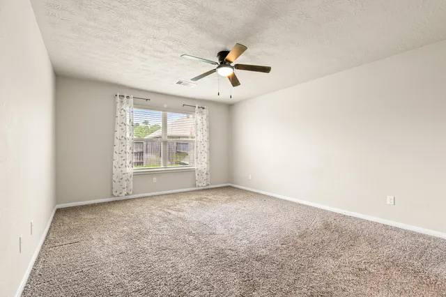 an empty room with windows and fan