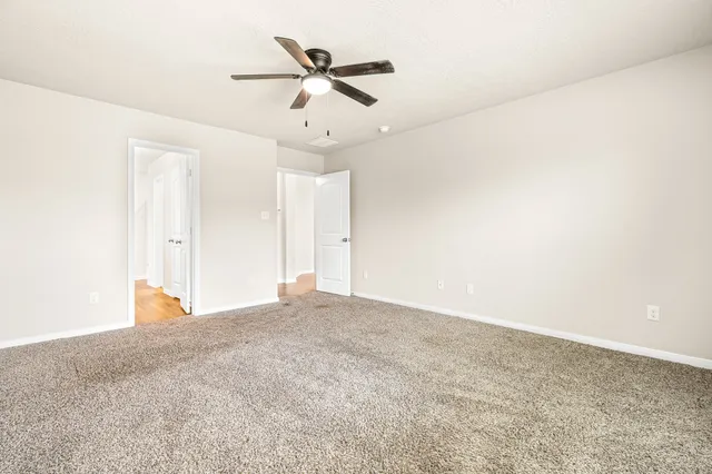 an empty room with ceiling fan and window