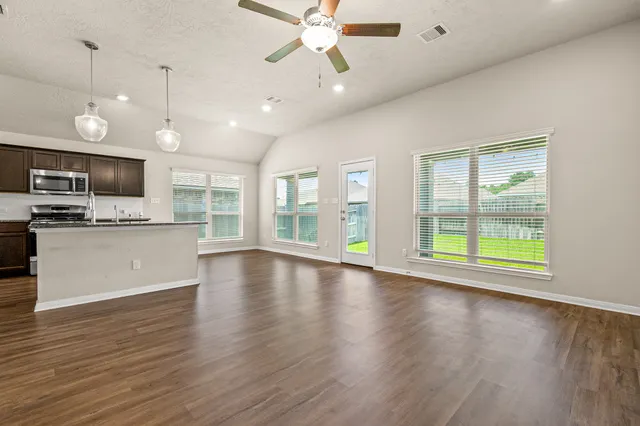 a view of an empty room with kitchen appliances and wooden floor