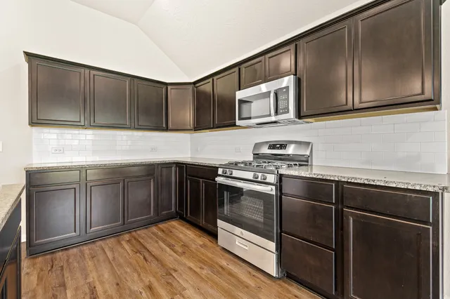 a kitchen with stainless steel appliances granite countertop a stove a sink and a microwave
