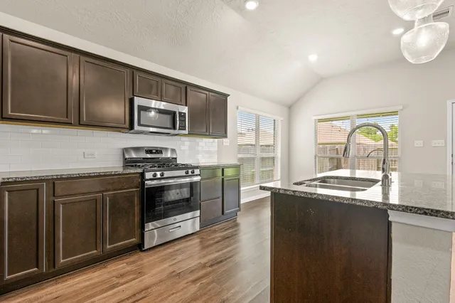 a kitchen with stainless steel appliances granite countertop a stove a sink and a microwave