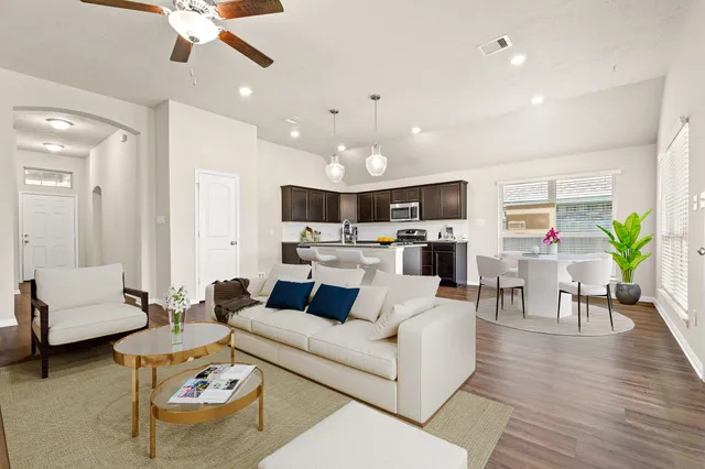 a living room with furniture kitchen view and a chandelier