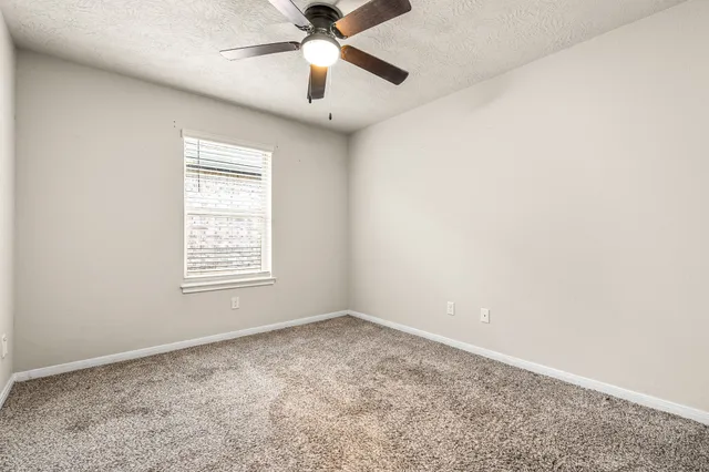 an empty room with a window and a fan