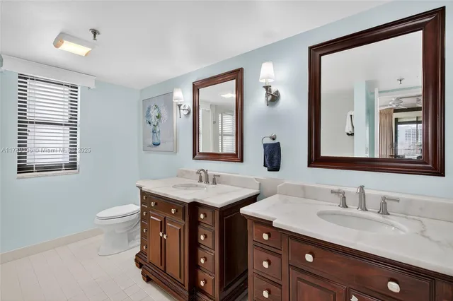 a bathroom with a toilet a sink a mirror and a window