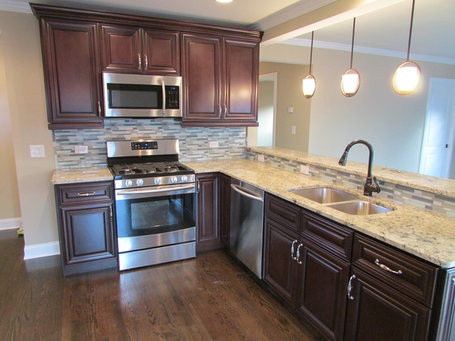 7719 East Prairie Road Skokie, IL 60076 - Photo 3 of 25 a kitchen with granite countertop a stove a microwave and wooden floor