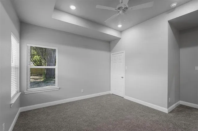 an empty room with a ceiling fan and windows