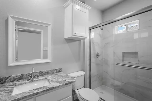 a bathroom with a granite countertop sink toilet and shower