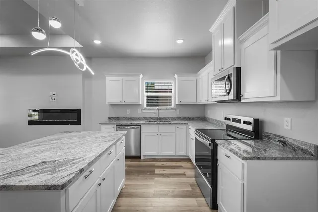 a kitchen with granite countertop cabinets stainless steel appliances and a counter space