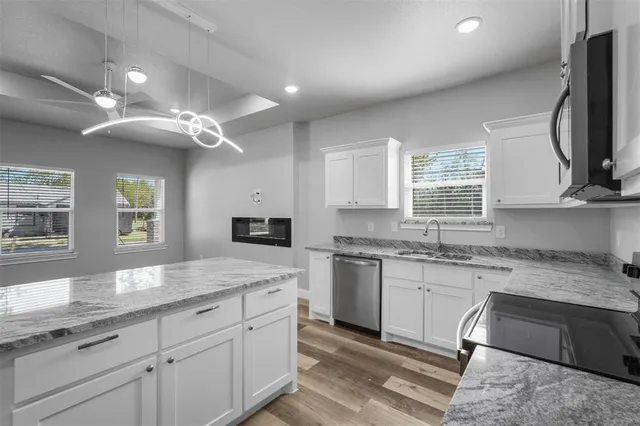 a kitchen with granite countertop cabinets stainless steel appliances a sink and a window