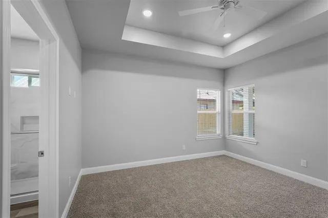 an empty room with windows and chandelier fan
