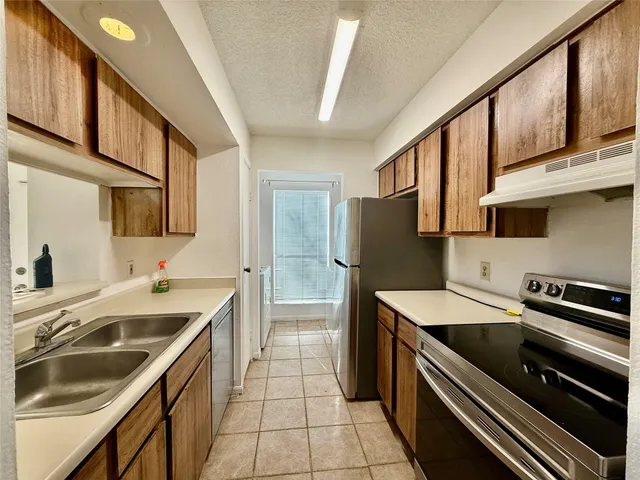 a kitchen that has a sink stainless steel appliances and cabinets