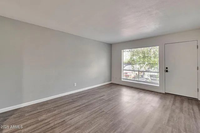 a view of an empty room with wooden floor and a window