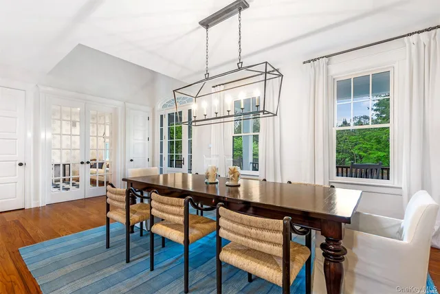 a dining room with wooden floor a chandelier a wooden table and chairs