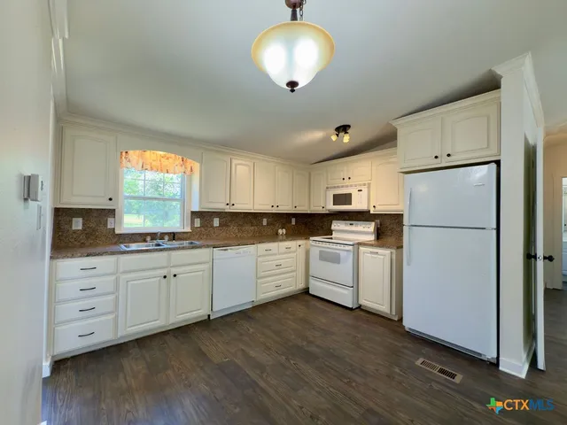 a kitchen with white cabinets and white appliances